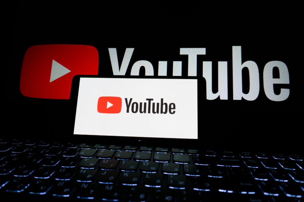 Canal no YouTube Sem Aparecer: Como Criar, Monetizar e Ganhar Dinheiro com o Método Dark Close-up of YouTube logo displayed on a laptop screen in a dark environment.