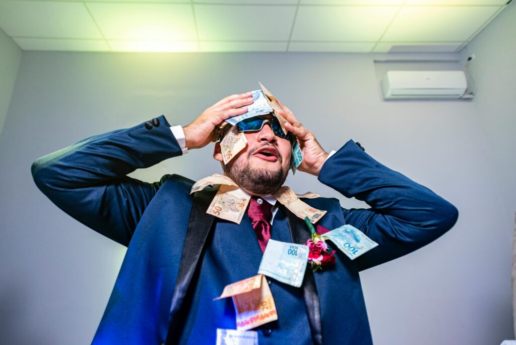 Como Evitar as Armadilhas dos Empréstimos Pessoais A joyful man in a suit with banknotes on him, celebrating indoors.