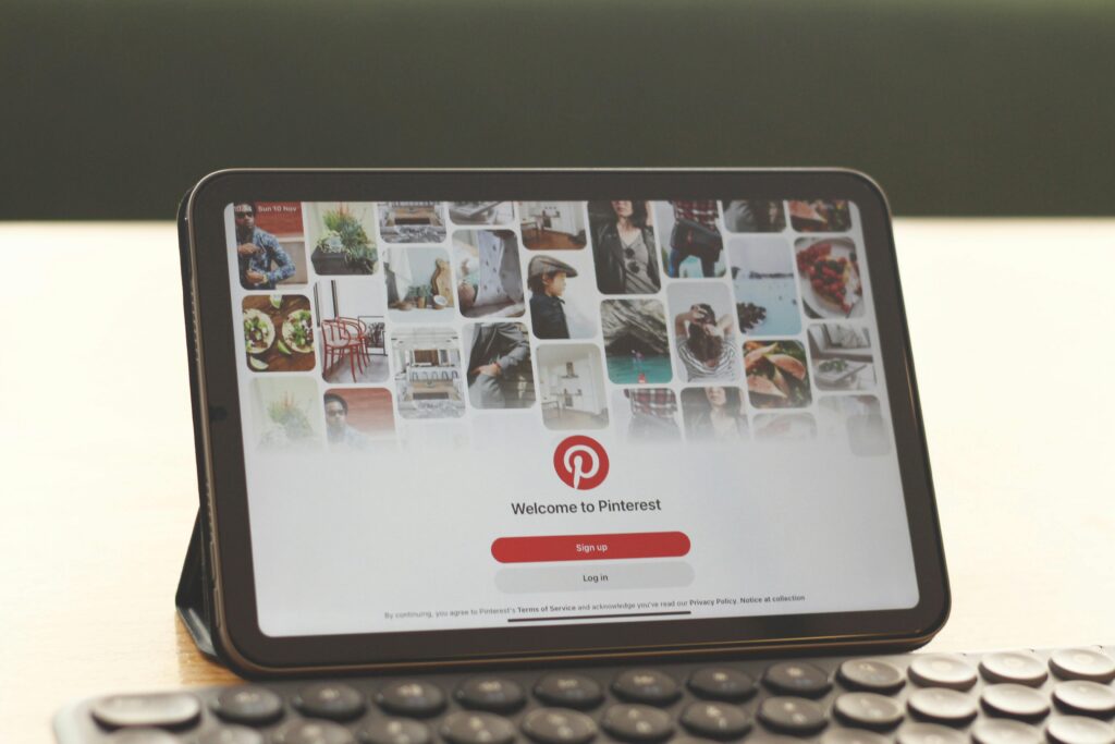 Como Trabalhar Com Pinterest e Ganhar Dinheiro de Casa Tablet showing Pinterest homepage on a modern desk setup with a keyboard.