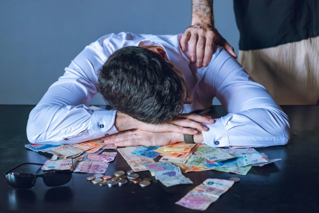 Poupança x CDB: Qual Realmente Vale Mais a Pena em 2026? Stressed businessman rests on table with Argentine pesos in Buenos Aires.