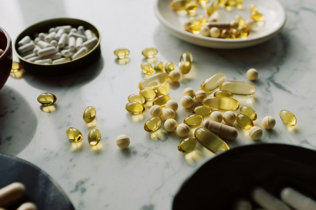 Vitamina D: Por Que Quase Todo Brasileiro Tem Deficiência e Não Sabe A close-up of assorted pills and supplements arranged on a marble surface, highlighting healthcare and wellness themes.