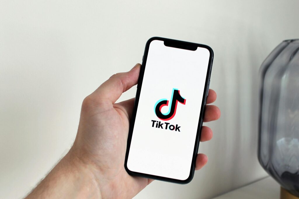 Como Ganhar Dinheiro com o TikTok Mesmo Sem Ser Famoso Close-up of a hand holding a smartphone displaying the TikTok app logo.
