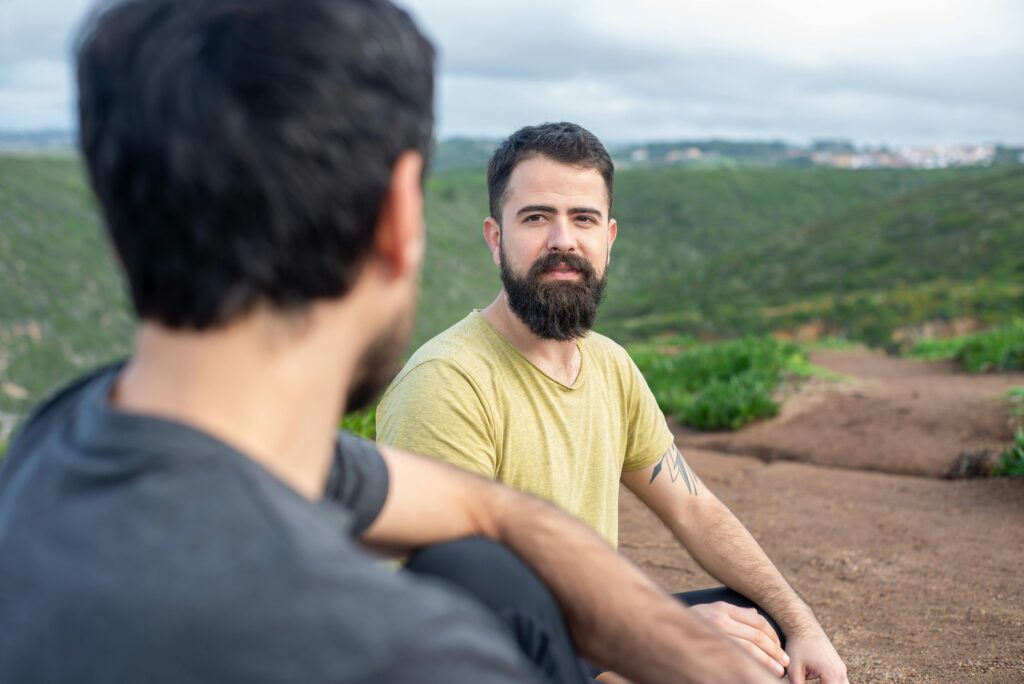Two men sitting on a hillside in Portugal, enjoying a relaxed conversation.
