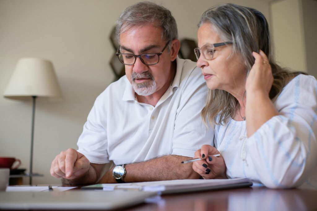 Quanto Você Precisa Juntar Para Se Aposentar Com Conforto? Elderly couple enjoying leisure time with crosswords at home, showcasing togetherness.