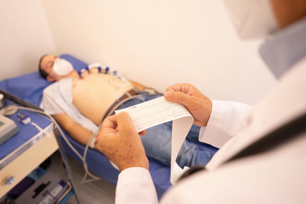 Colesterol: O Que os Exames Realmente Significam e O Que Fazer A doctor analyzes an ECG printout while a patient undergoes monitoring in a medical clinic.
