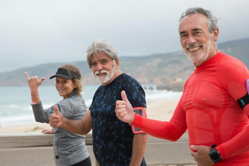 Longevidade: Os Hábitos de Quem Vive Mais de 90 Anos Com Saúde Smiling senior friends exercising on a beach in Portugal, embracing a healthy lifestyle.