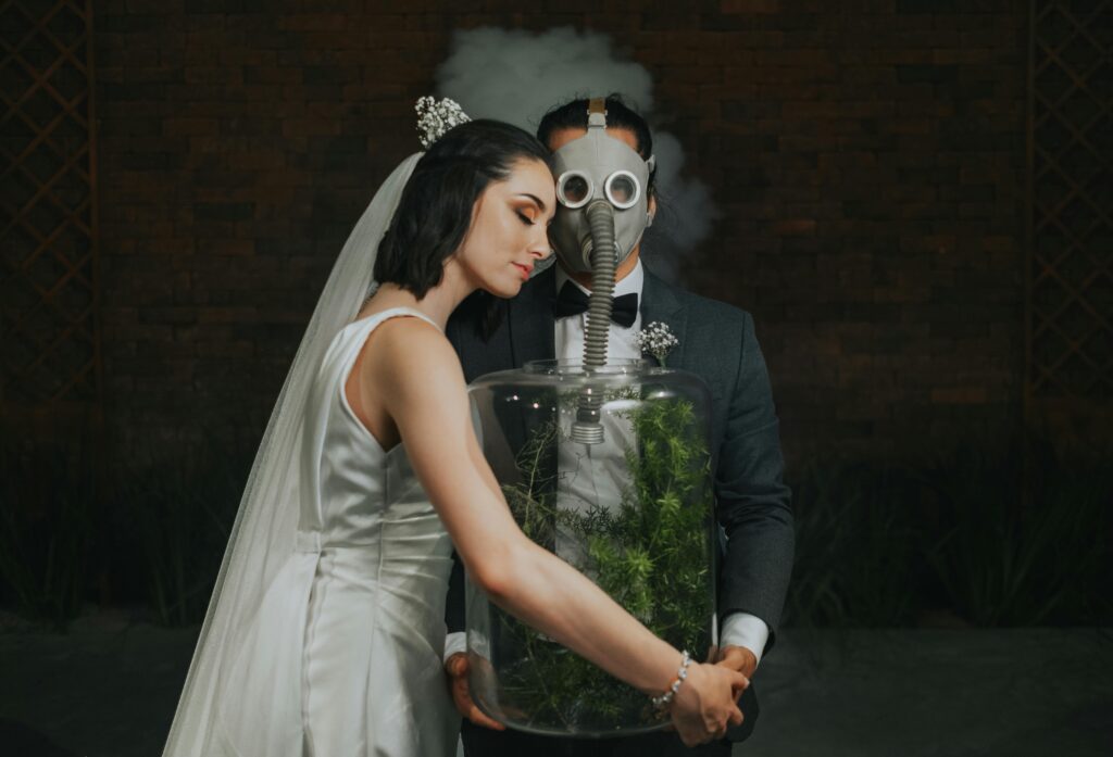 5 Sinais de Que Você Está em Um Relacionamento Tóxico Sem Perceber A creative wedding photo featuring a bride and groom in a studio with a gas mask and glass jar.