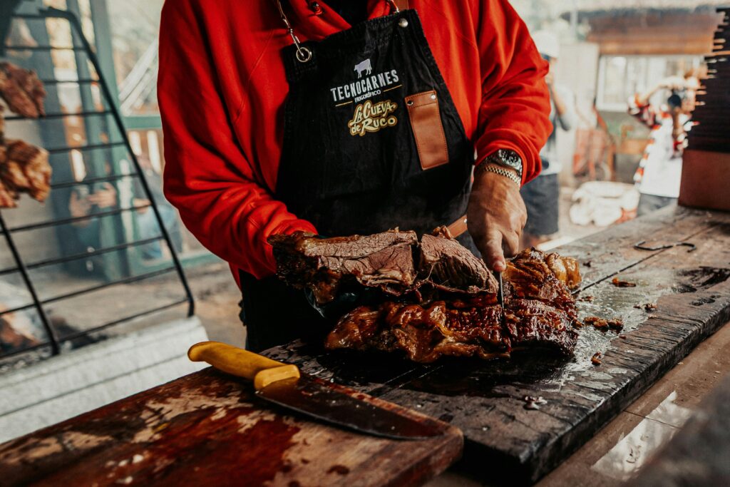 A cook preparing traditional Argentine asado with grilled beef slices in Provincia de Buenos Aires, Argentina.