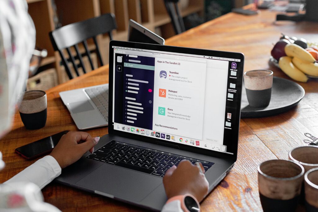 Person using laptop in cozy workspace with coffee and fruits. Perfect for remote work themes.